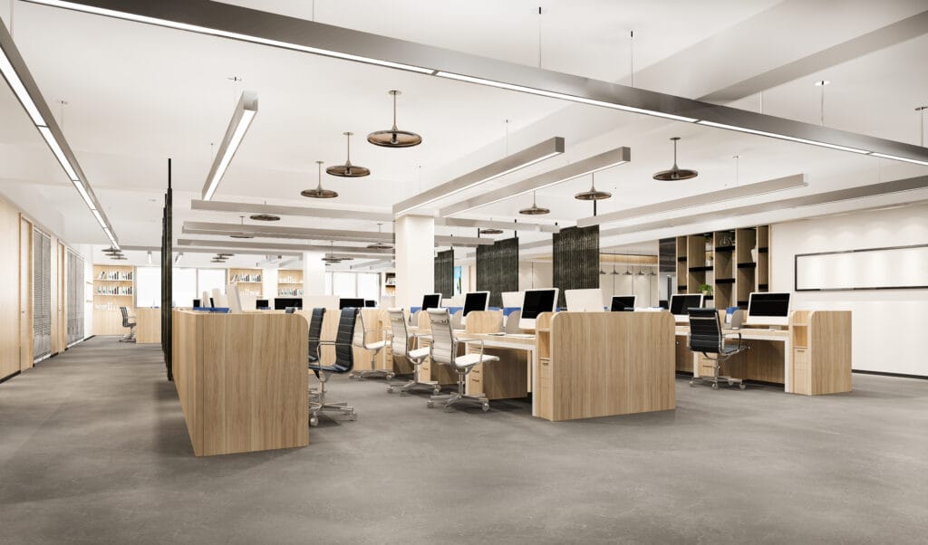 Empty open-plan office with wooden desks, black and white chairs, and ceiling lights.