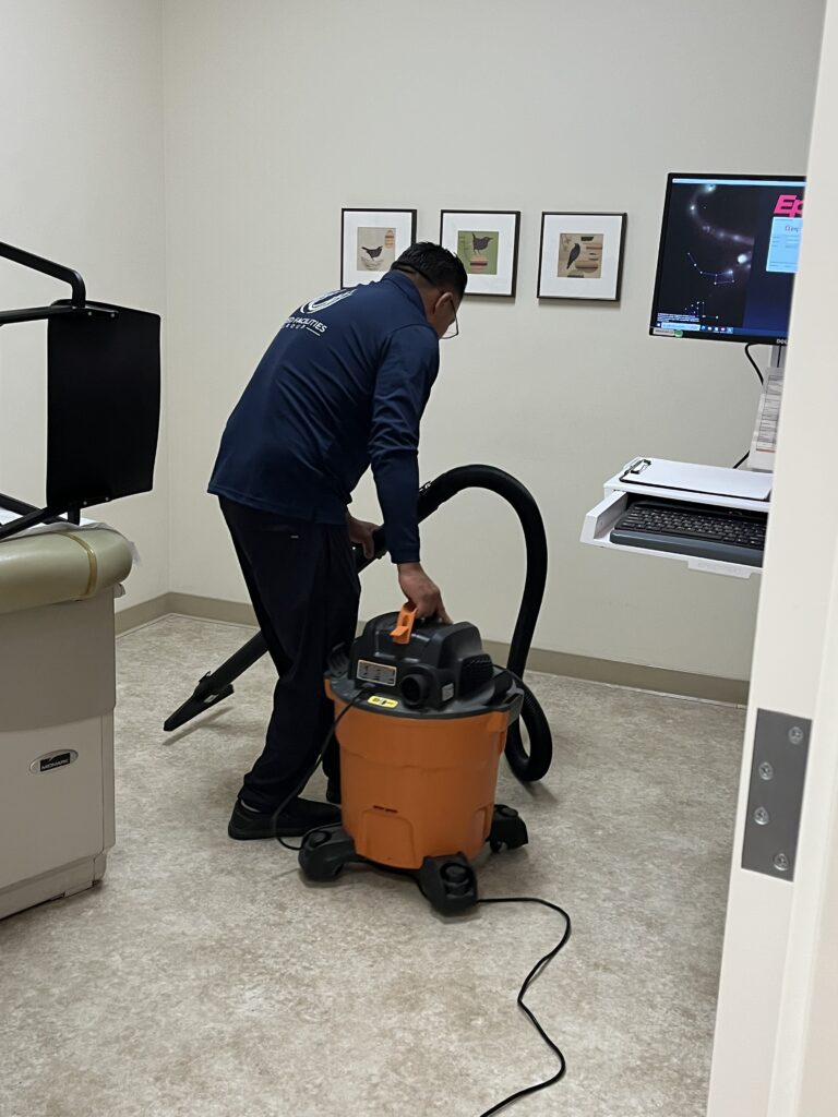 Person cleaning with a vacuum cleaner in a medical office room.